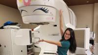 Radiation therapist Adeline Li stands next to radiation machine decorate like a unicorn.